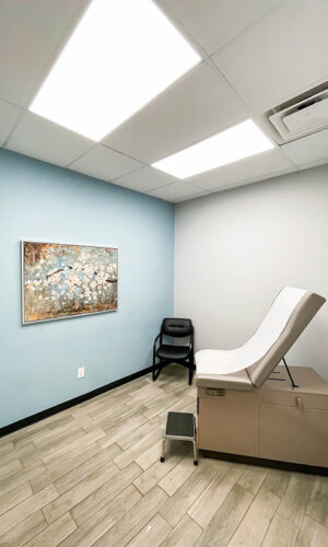 A photo of a beautiful room with a wooden-tiled floor and artwork on the wall used for patient care at Swift Health Morrow