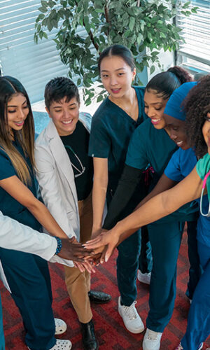 A Swift Health Morrow team celebrating teamwork with by putting their hands together in a circle