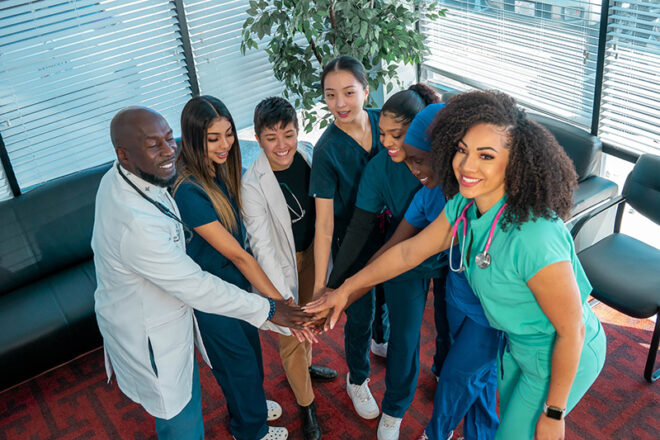 A Swift Health Morrow team celebrating teamwork with by putting their hands together in a circle